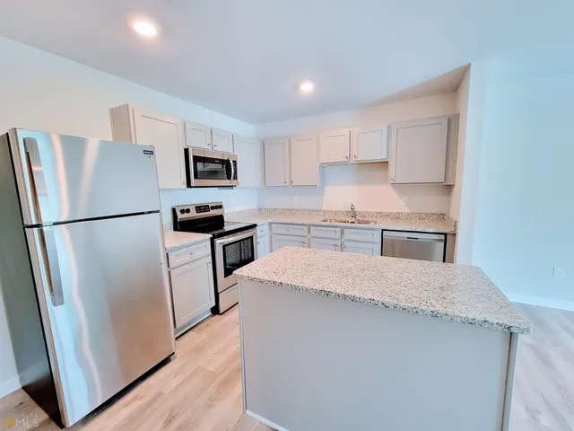 a kitchen with granite countertop a refrigerator and a sink