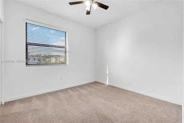 an empty room with a window and a ceiling fan