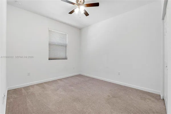 an empty room with a window and a fan