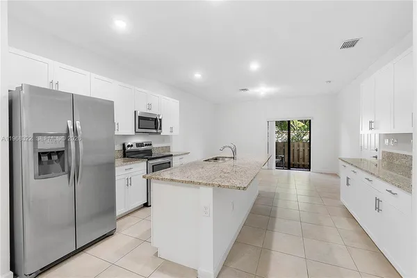 a large kitchen with a large counter top stainless steel appliances and cabinets