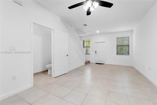 an empty room with chandelier fan and windows