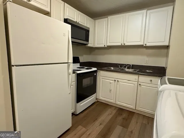 a white refrigerator freezer and a stove sitting inside of a kitchen with granite countertop stainless steel appliances