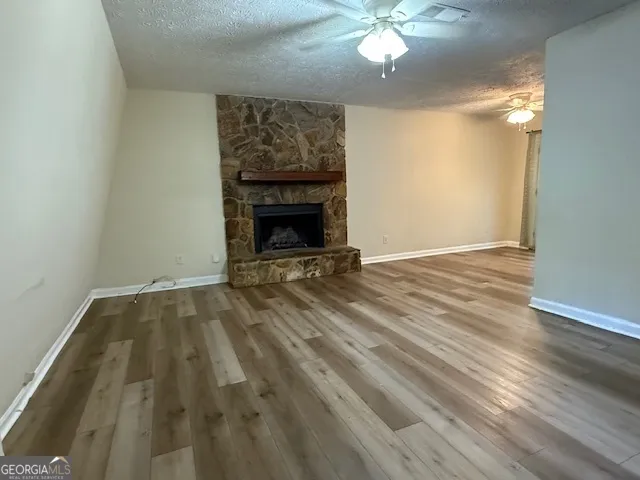 a view of an empty room with wooden floor a fireplace and a window