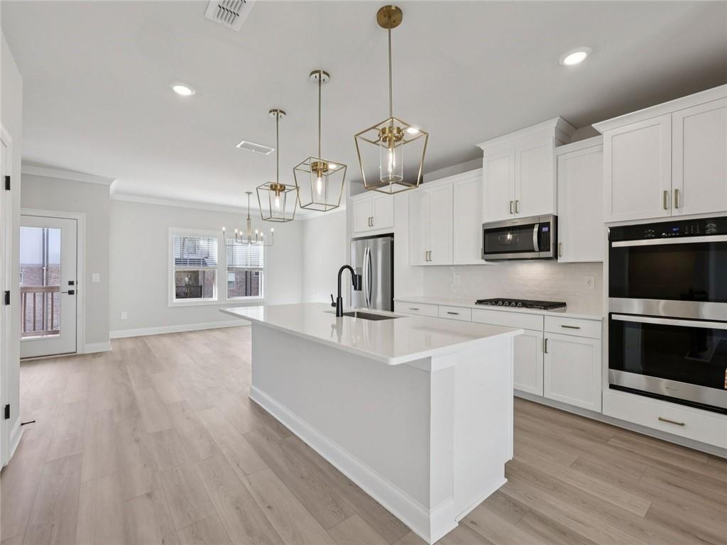 508 McCrae Road Lawrenceville, GA 30045 - Photo 6 of 22 a kitchen with kitchen island white cabinets stainless steel appliances and wooden floor