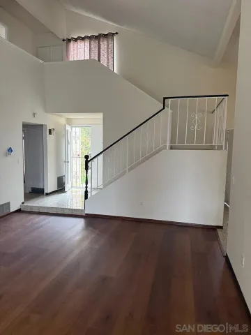 a view of an empty room with wooden floor and a fireplace