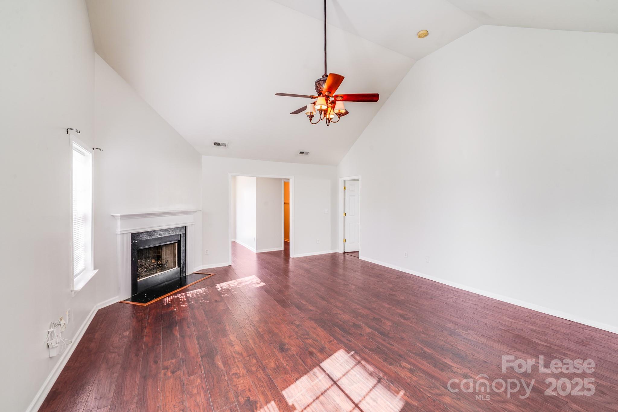 1427 Jabbok Place Northwest Concord, NC 28027 - Photo 11 of 30 an empty room with wooden floor fireplace and windows