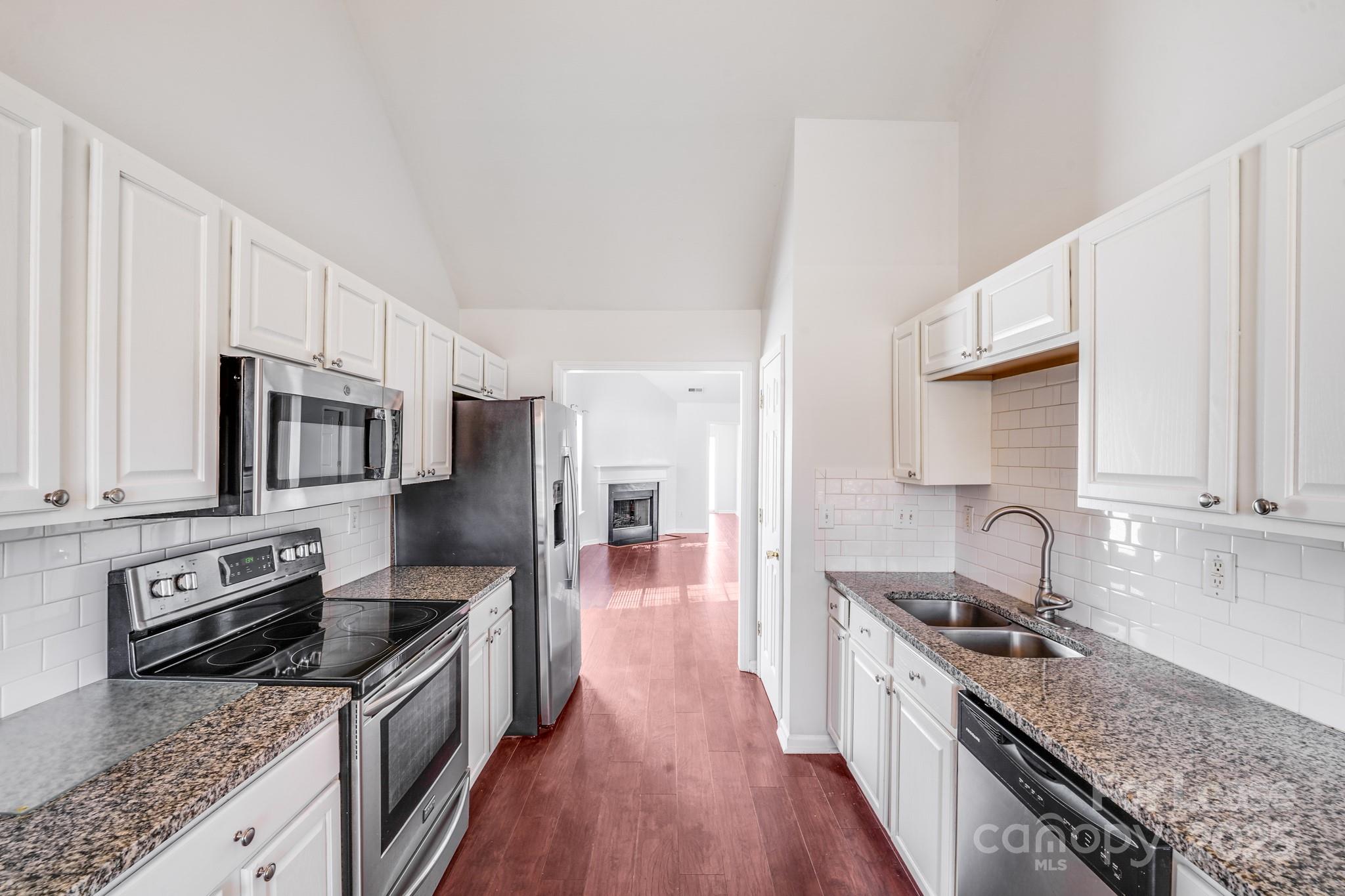 1427 Jabbok Place Northwest Concord, NC 28027 - Photo 3 of 30 a kitchen with stainless steel appliances granite countertop a stove top oven a sink dishwasher a refrigerator and cabinets with wooden floor