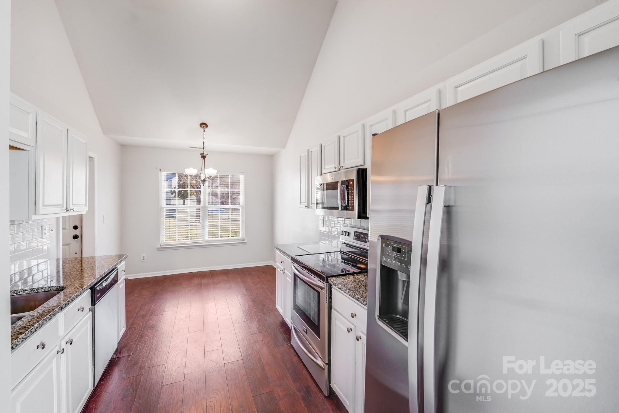 1427 Jabbok Place Northwest Concord, NC 28027 - Photo 10 of 30 a kitchen with stainless steel appliances a refrigerator a stove a sink and wooden floors