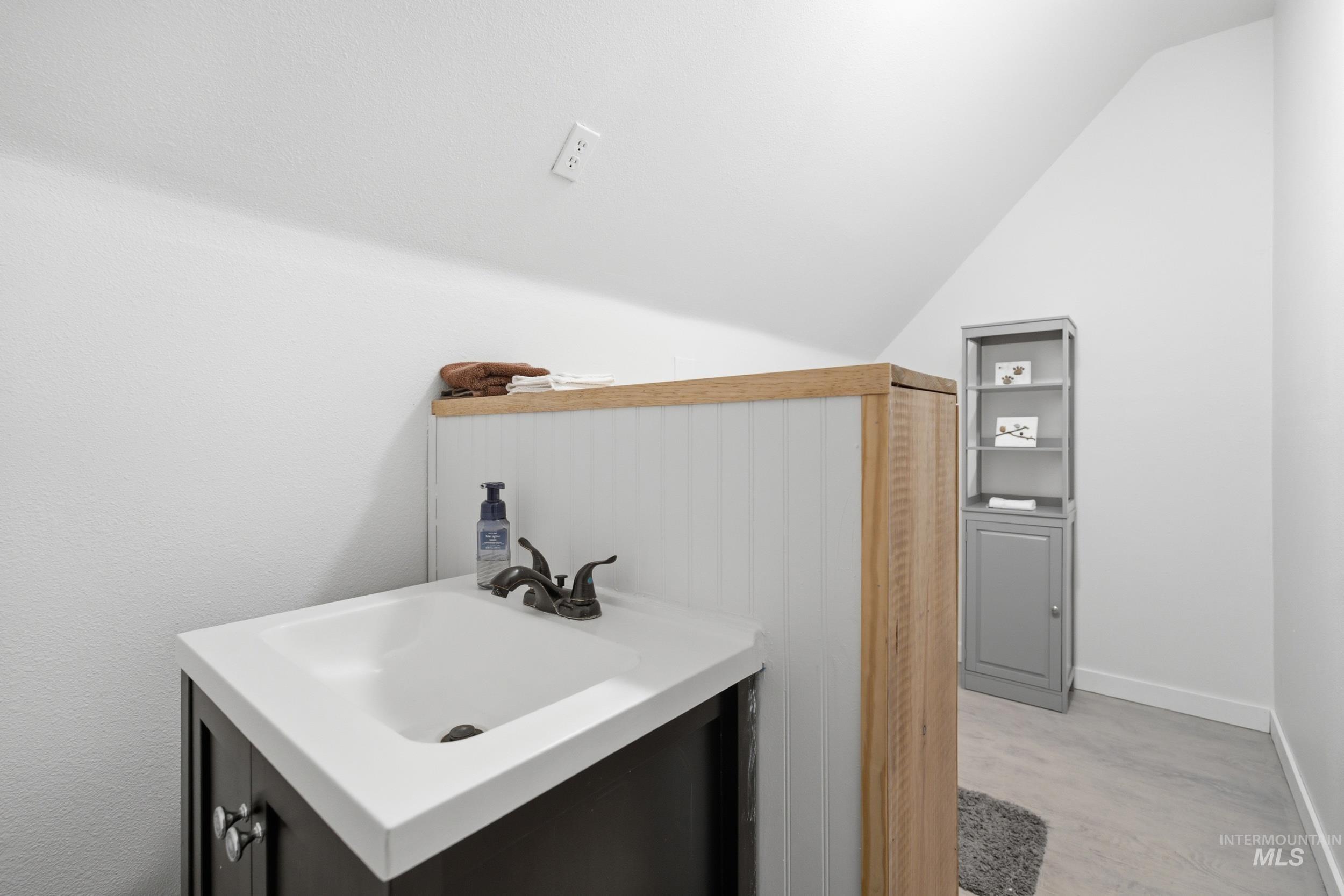 3980 North Pine-Featherville Road Mountain Home, ID 83647 - Photo 30 of 35 Bathroom vanity with a white integrated sink and dark cabinet base, featuring a bronze-finish faucet