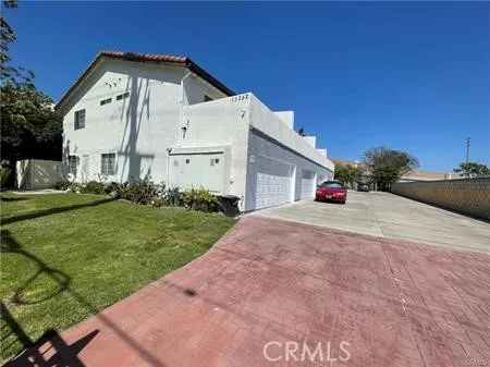 a view of a white house with a big yard and potted plants