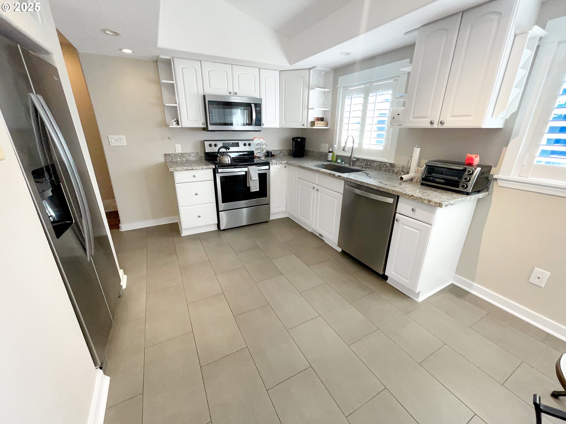 4535 Southwest Laurelwood Avenue Portland, OR 97225 - Photo 4 of 10 a kitchen with stainless steel appliances white cabinets a sink a stove a refrigerator and a window