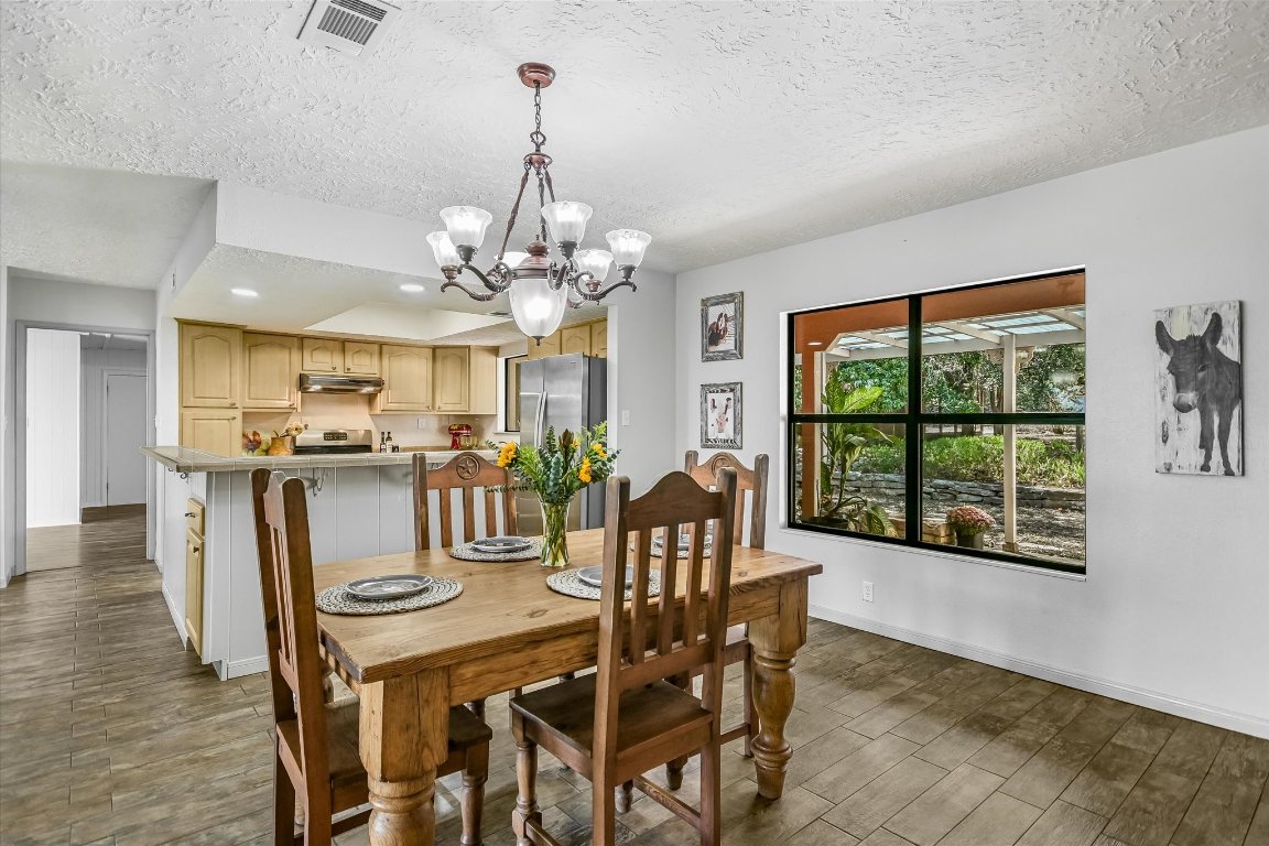 175 Fischer Trail Wimberley, TX 78676 - Photo 7 of 33 a view of a dining room with furniture a chandelier and wooden floor