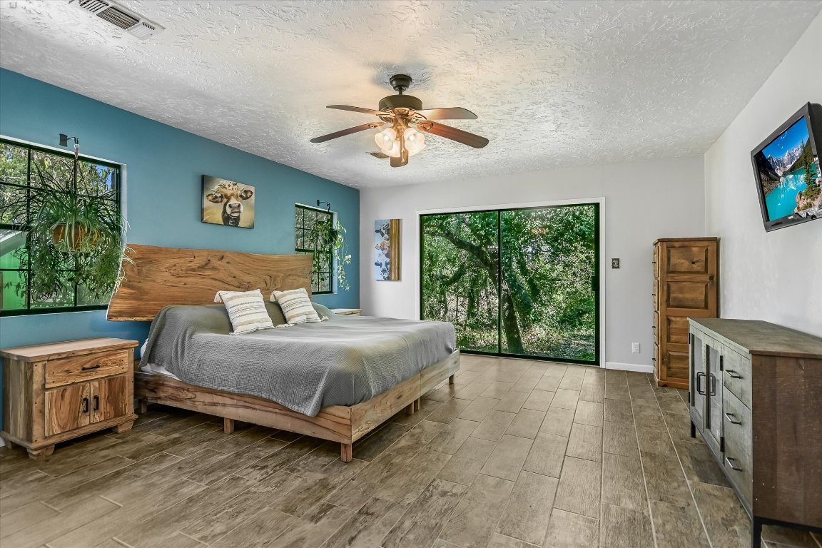 175 Fischer Trail Wimberley, TX 78676 - Photo 10 of 33 a spacious bedroom with a bed and a chandelier