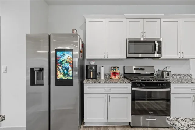 a kitchen with stainless steel appliances granite countertop a stove a microwave and a refrigerator