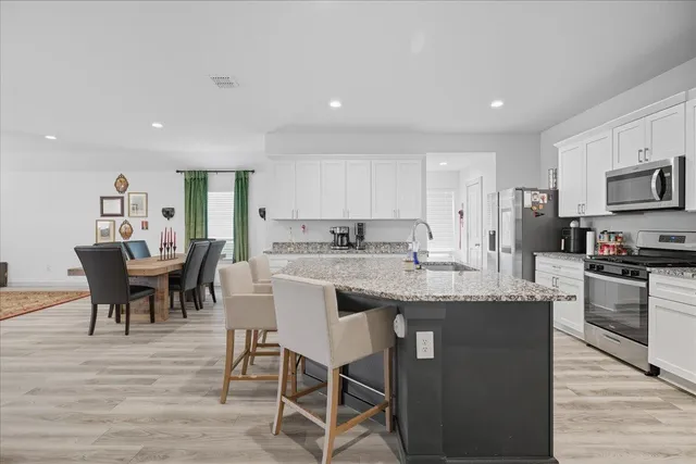 a kitchen with kitchen island granite countertop a table chairs sink and microwave