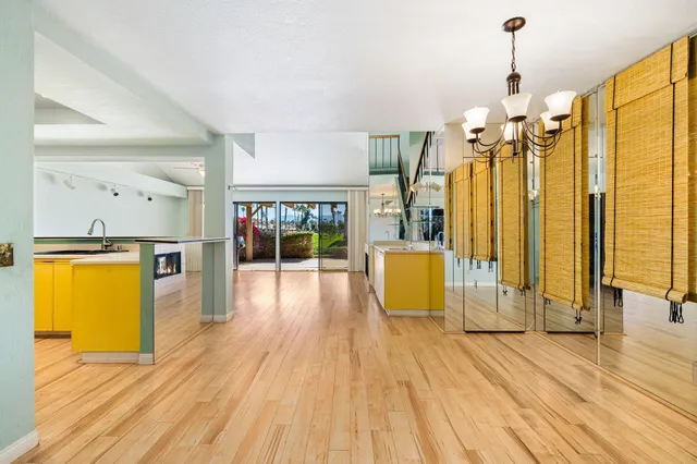 a view of a kitchen with kitchen island wooden floor and stainless steel appliances