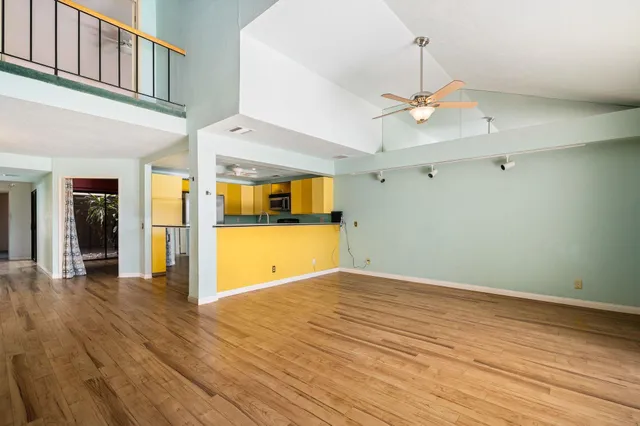 a view of a kitchen with kitchen island wooden floor and stainless steel appliances