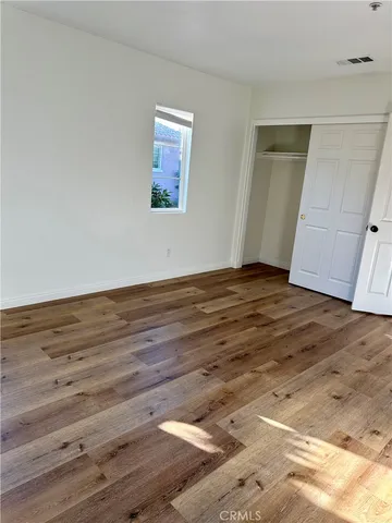 a view of an empty room with wooden floor and closet