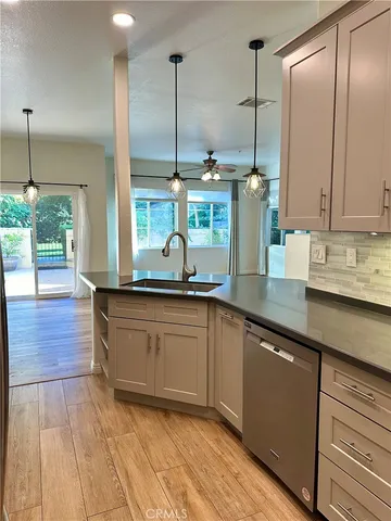 a kitchen with stainless steel appliances granite countertop a sink a stove and a wooden floor