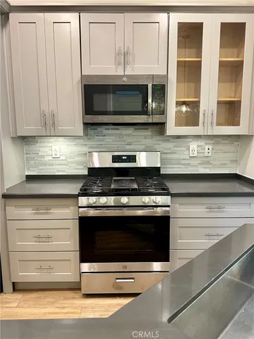 a kitchen with granite countertop a stove microwave and cabinets
