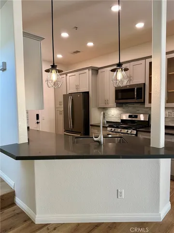 a kitchen with stainless steel appliances granite countertop a sink a stove and a refrigerator