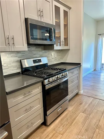 a kitchen with granite countertop cabinets stainless steel appliances and wooden floor