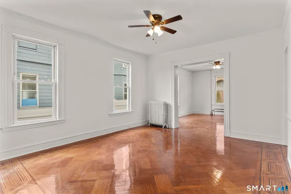 a view of empty room with wooden floor and fan