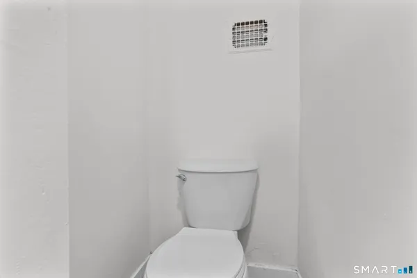 a white toilet sitting next to a white wall