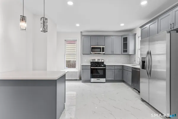 a kitchen with kitchen island a counter top space stainless steel appliances and cabinets