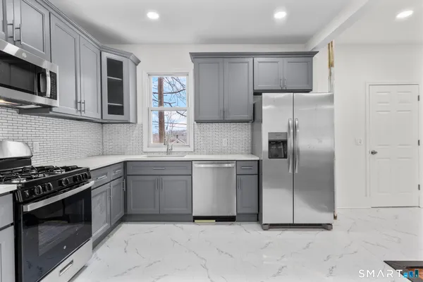 a kitchen with stainless steel appliances granite countertop a refrigerator a stove a sink and a microwave