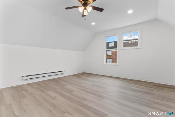 an empty room with wooden floor chandelier fan and windows