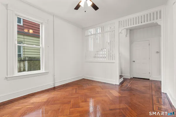 an empty room with chandelier fan and windows