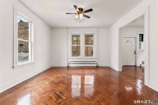 a view of an empty room with a window and a kitchen