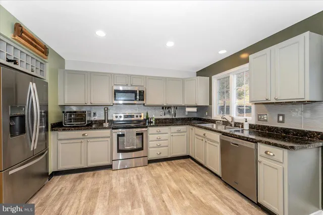 a kitchen with stainless steel appliances kitchen island granite countertop a table chairs and a refrigerator