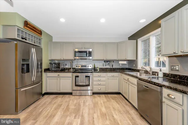 a kitchen with stainless steel appliances kitchen island granite countertop white cabinets and wooden floor