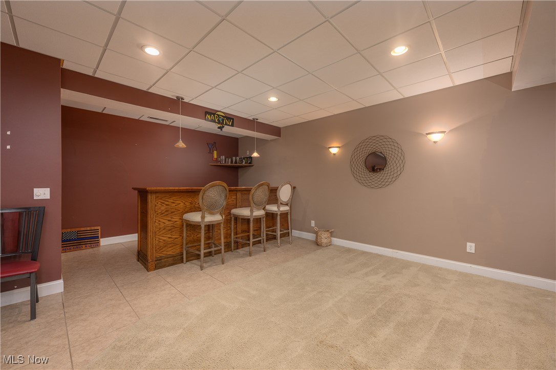 6986 Sweetwater Road Northeast Canton, OH 44721 - Photo 19 of 36 Family Room featuring bar area, wall sconces, tile and carpeted flooring