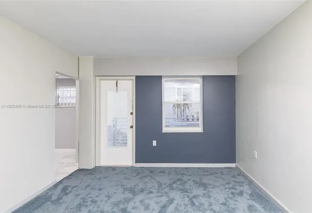 a view of an empty room with window and closet area