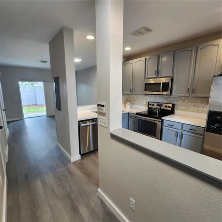 a kitchen with stainless steel appliances a sink cabinets and wooden floor