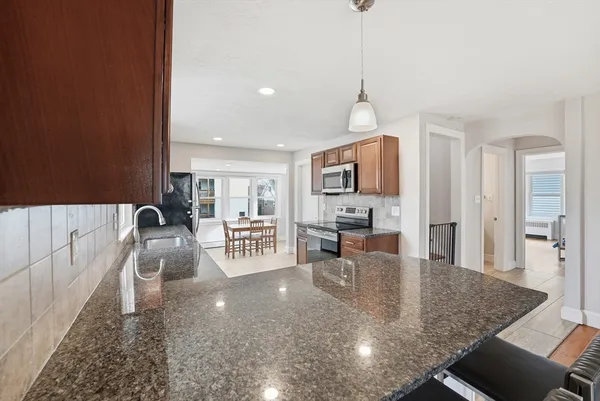 a large kitchen with stainless steel appliances granite countertop a stove a sink dishwasher and a refrigerator with wooden floor