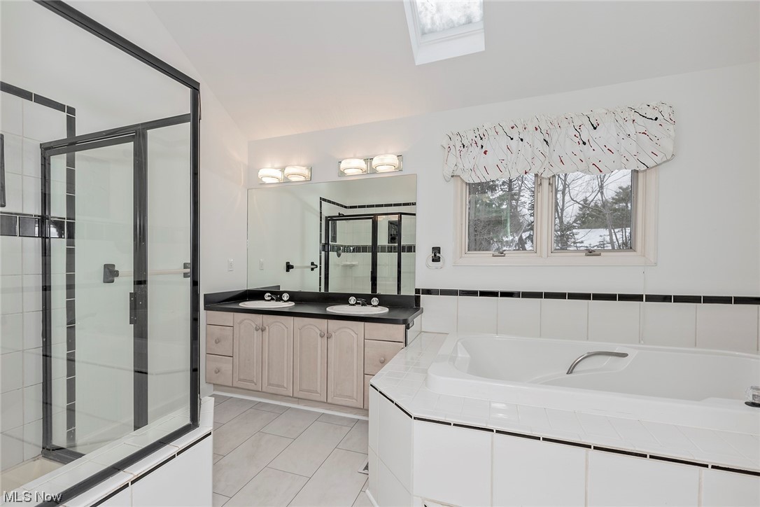 3850 Ellendale Road Moreland Hills, OH 44022 - Photo 23 of 39 Bathroom featuring ceramic tile flooring, shower and Jetted bathtub, vaulted ceiling with skylight, double sink, and large vanity