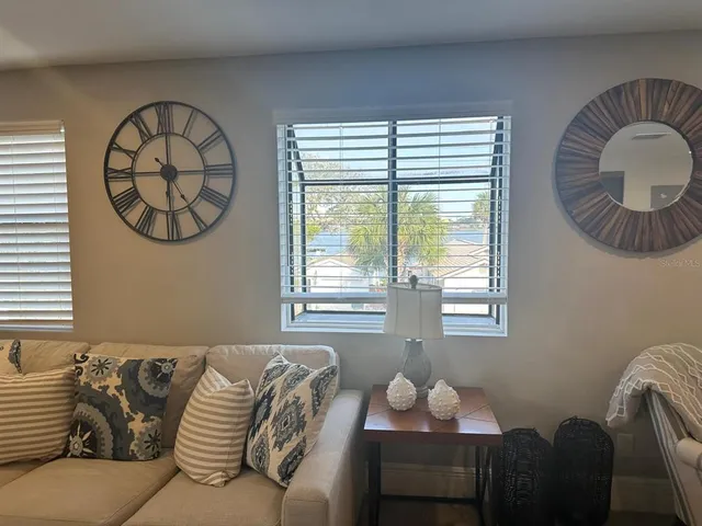 a living room with stainless steel appliances furniture a rug and a window