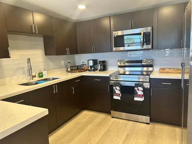 a kitchen with stainless steel appliances granite countertop white cabinets and a stove top oven