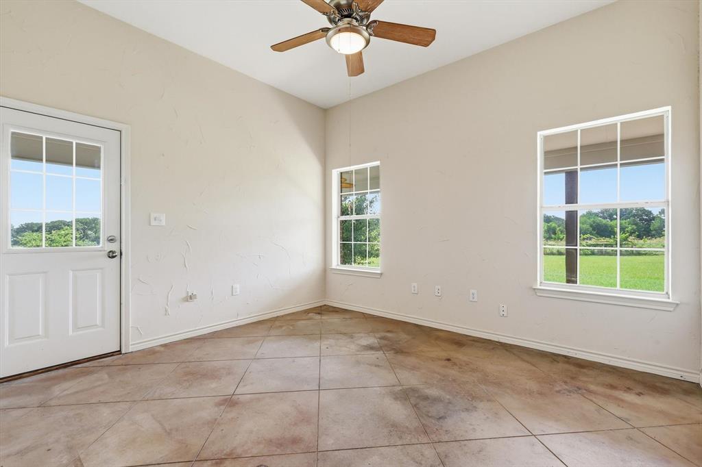 12190 Bell Road Pilot Point, TX 76258 - Photo 31 of 39 Open-concept room featuring a ceiling fan with light fixture, two windows, and a glass-paneled door