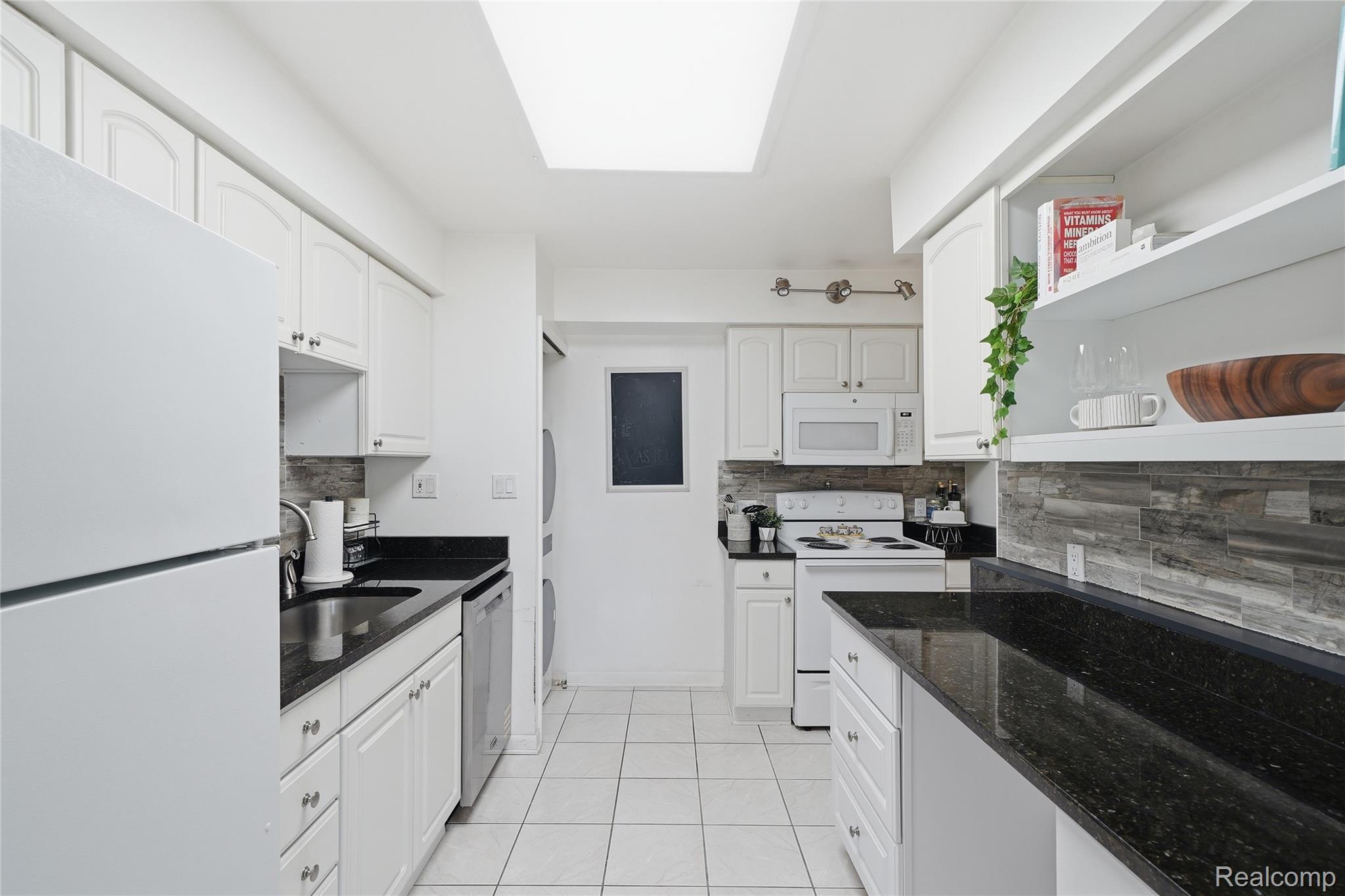 4041 West Maple Road, Unit E203 Bloomfield Hills, MI 48301 - Photo 14 of 25 Kitchen featuring white appliances, backsplash, and white cabinetry