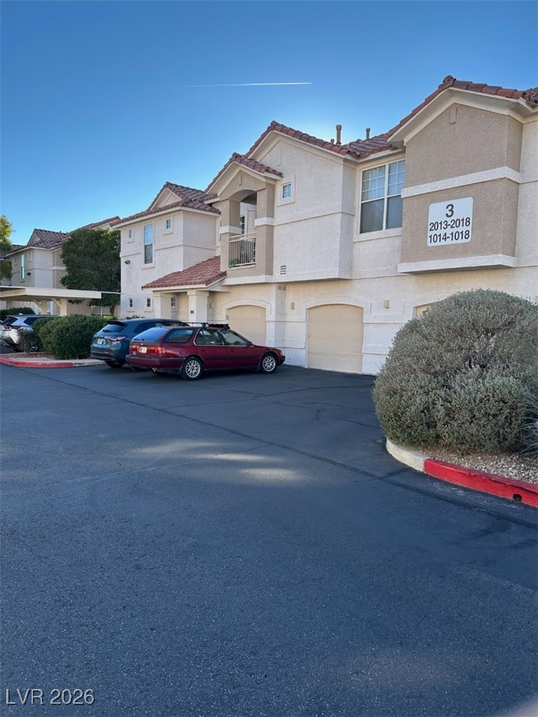 8555 West Russell Road, Unit 2018 Las Vegas, NV 89113 - Photo 3 of 31 Mediterranean / spanish-style house featuring stucco siding, a garage, driveway, and a residential view