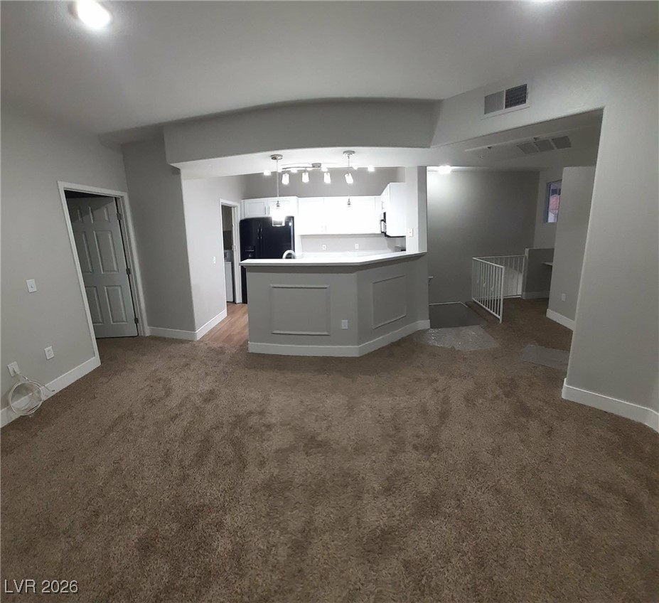 8555 West Russell Road, Unit 2018 Las Vegas, NV 89113 - Photo 9 of 31 Kitchen with a peninsula, black fridge, pendant lighting, white cabinetry, and light countertops