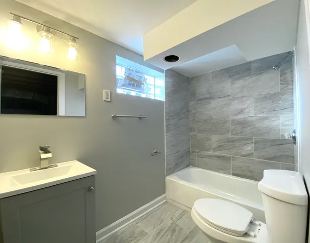 a bathroom with a toilet a sink a mirror and bathtub