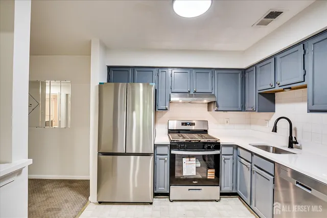a kitchen with stainless steel appliances a refrigerator sink and white cabinets