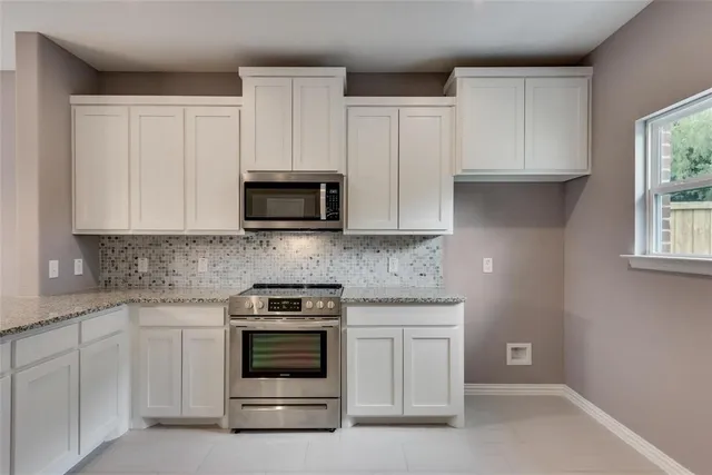 a kitchen with white cabinets and stainless steel appliances