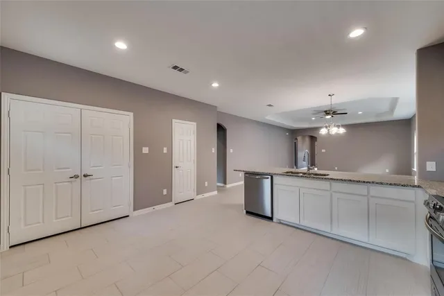 a large kitchen with stainless steel appliances granite countertop a sink and dishwasher with white cabinets
